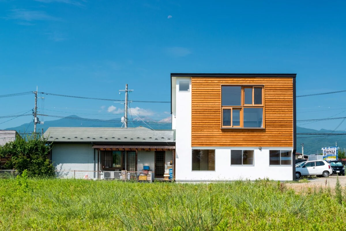 ご実家の敷地内、ご両親が住まう平屋に寄り添うように建てられた狭小2階建て。休耕田が広がる東側の開けた眺めを借景として取り入れるため、2階LDKに大きな窓を設けている