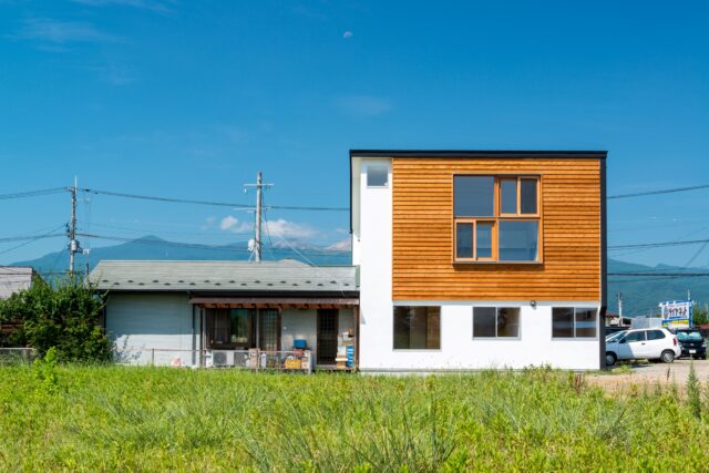 ご実家の敷地内、ご両親が住まう平屋に寄り添うように建てられた狭小2階建て。休耕田が広がる東側の開けた眺めを借景として取り入れるため、2階LDKに大きな窓を設けている