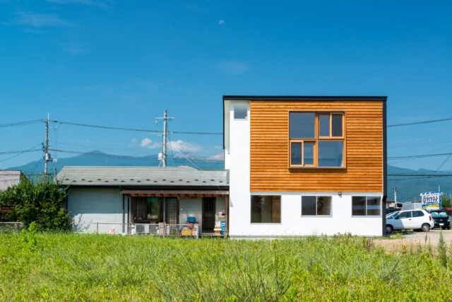ご実家の敷地内、ご両親が住まう平屋に寄り添うように建てられた狭小2階建て。休耕田が広がる東側の開けた眺めを借景として取り入れるため、2階LDKに大きな窓を設けている
