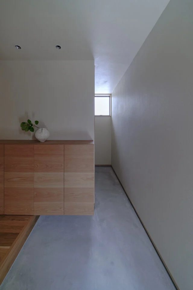 玄関土間。窓から入る光で漆喰壁の質感が際立つ。奥はキャンプ用品などをしまえる土間収納