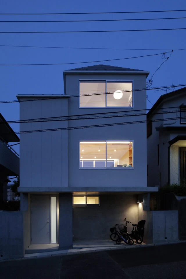 夜になると、RCの土台、大小２つの棟の趣の違いがより一層際立つ。高さがあるため、１階リビングの様子も道路から丸見えにならない。