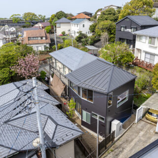 画像中央、黒い外壁の建物が「鎌倉山の住宅Ⅱ」。奥に続く白い外壁の家は息子さま家族が暮らす既存建物。高台にあり家に囲まれている立地から多くの法的制限がかかるため様々な困難が予想され、当初は依頼を請けるハウスメーカーや施工会社が見つからなかった