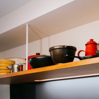 キッチンのオープン吊戸棚。見せる収納だけでなく、サイズが大きい鍋なども収納できる利点がある。棚の木はキッチンと同じもの。多くの素材を使わず、統一感とシンプルさを追求した。