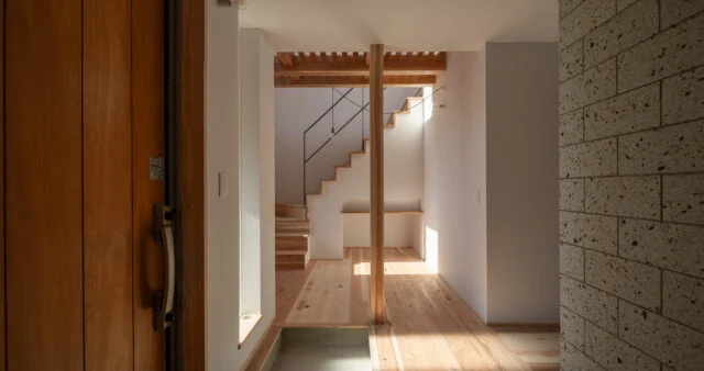 玄関ホール。木材は無垢の杉、白壁はドイツ製のウッドチップ入り紙クロス。自然志向の素材を使ったナチュラルモダンな空間に、大谷石の壁（写真右）が本物志向の上質感をプラス。過度にならない上品な高級感がいい