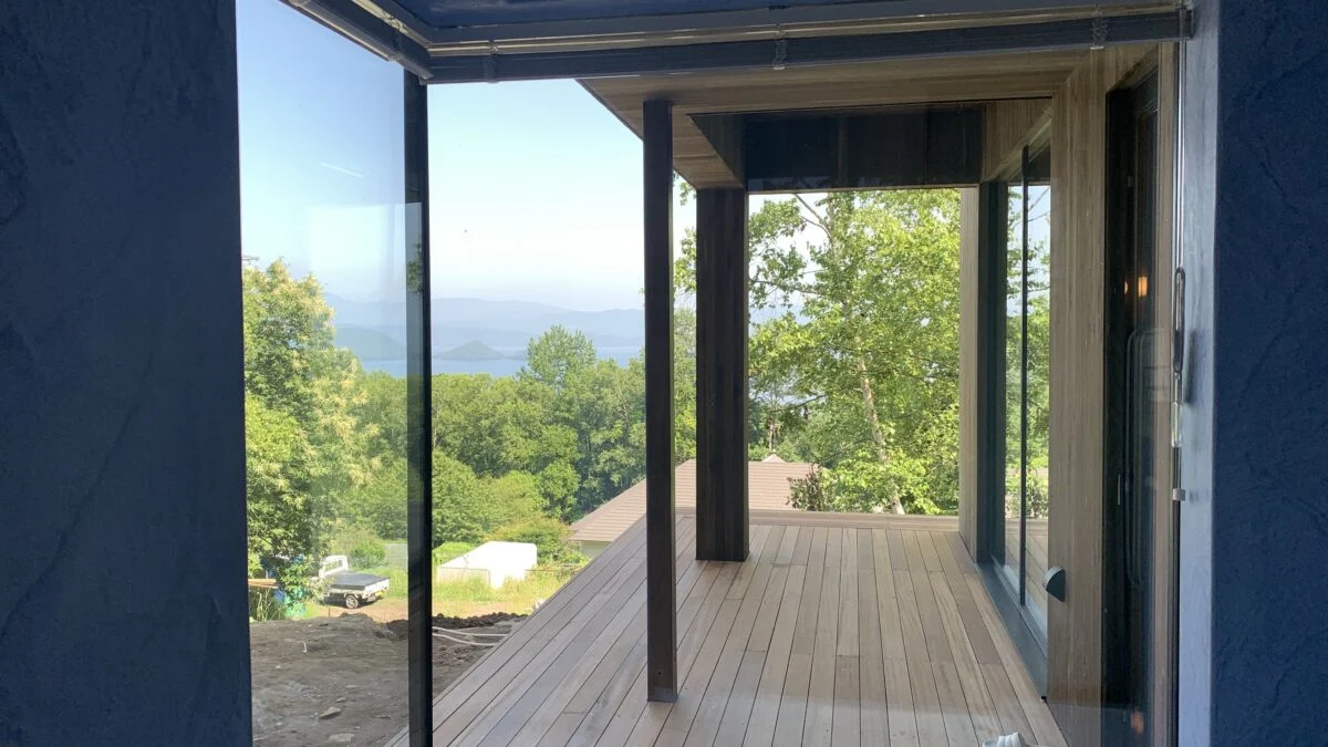 1階浴室からテラスを見る。屋根があるテラスは天候関係なくくつろげる。左隣で暮らす義理のご家族とも、ここで交流することがあるのだとか。浴室は要望からブルーで仕上げた。絶景のお風呂はお施主さまもお気に入りの場所の1つ