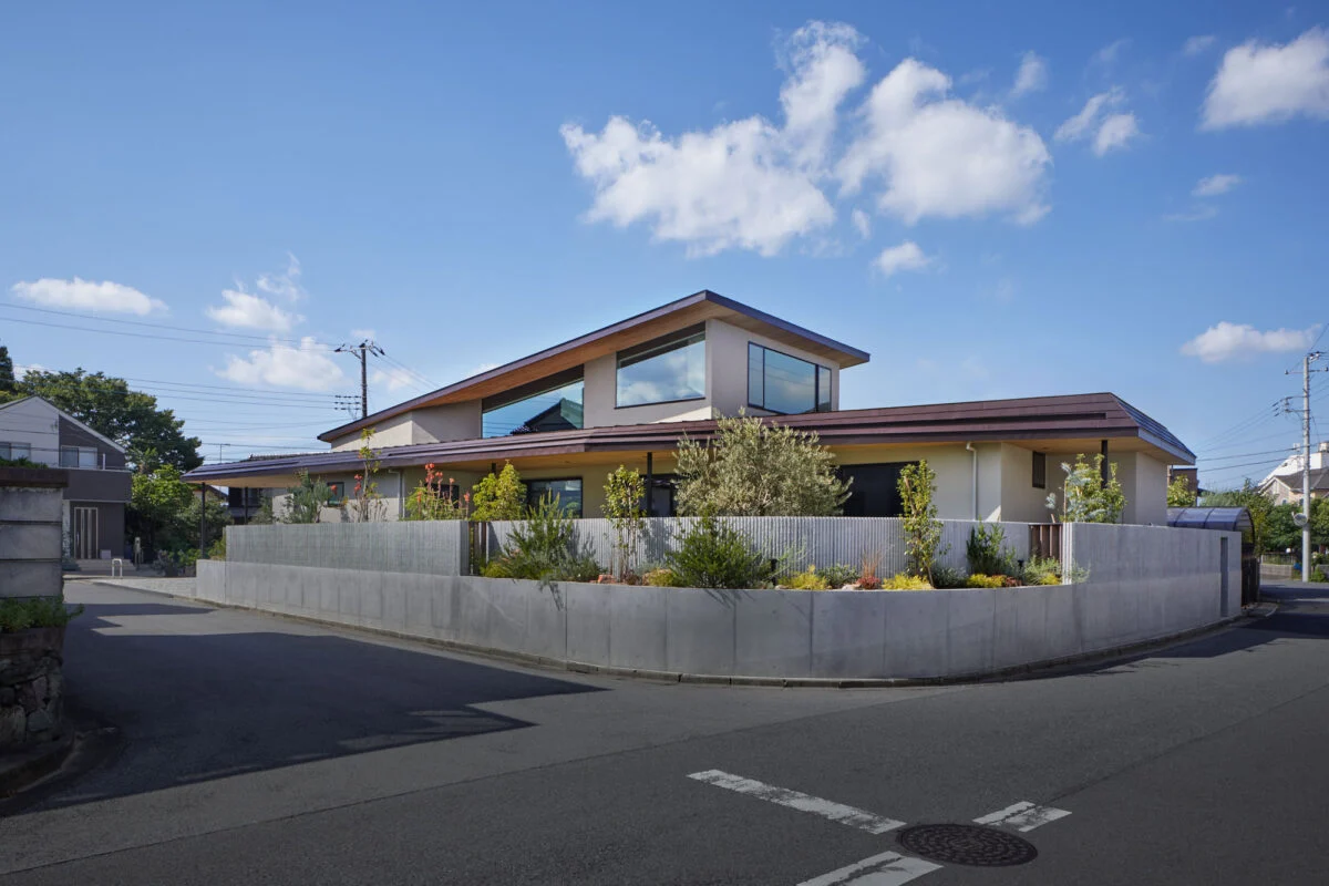 南から見た外観。プライバシーを守るための外構は、一部の植栽は道路に向けて開き威圧感を軽減。コンクリートはリブ付きとし、柔らかさをプラスした。まっすぐに伸びる１階の屋根と、捲り上がるような２階の屋根。どちらも伸びやかで、家に大らかさが感じられる