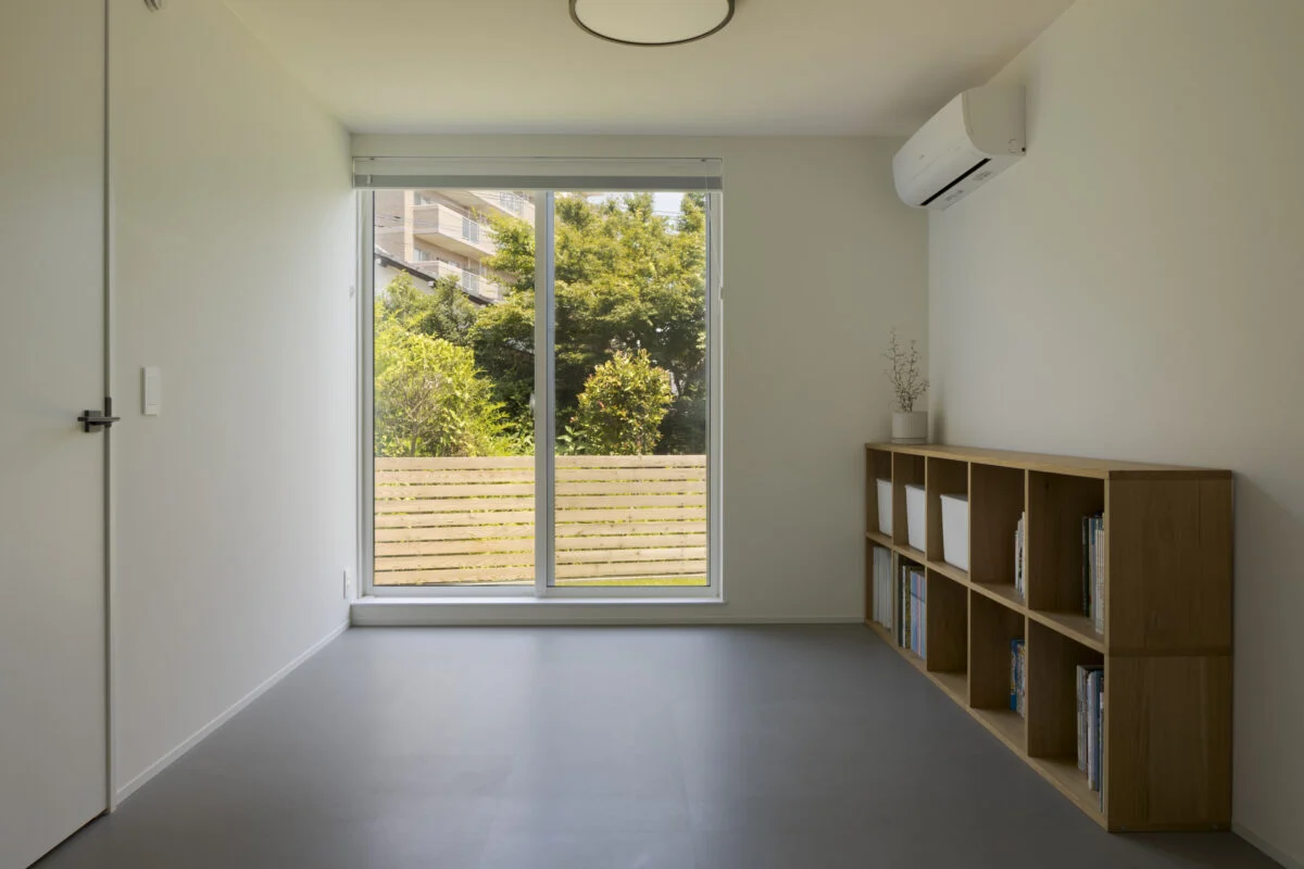 1階寝室は、将来2部屋に分けることができる。将来、車いすが必要になった場合などに備えて1階のどこかは掃き出し窓にしたかったと2人。庭のフェンスは宏昌さんがDIYした。1階は全体的に同じフロアタイルを敷き、設えの雰囲気アップとコストダウンを同時に実現