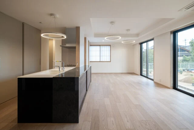 1階のLDK。キッチンの手前と奥、それぞれの通路が玄関へとつながる回遊動線を計画している。家族が集う空間は思い思いにくつろげるよう、シンプルなつくりとした。キッチンは奥様の要望で、造作家具の高さを揃えたフラットなデザインとし、LDK全体を見渡しやすくしている