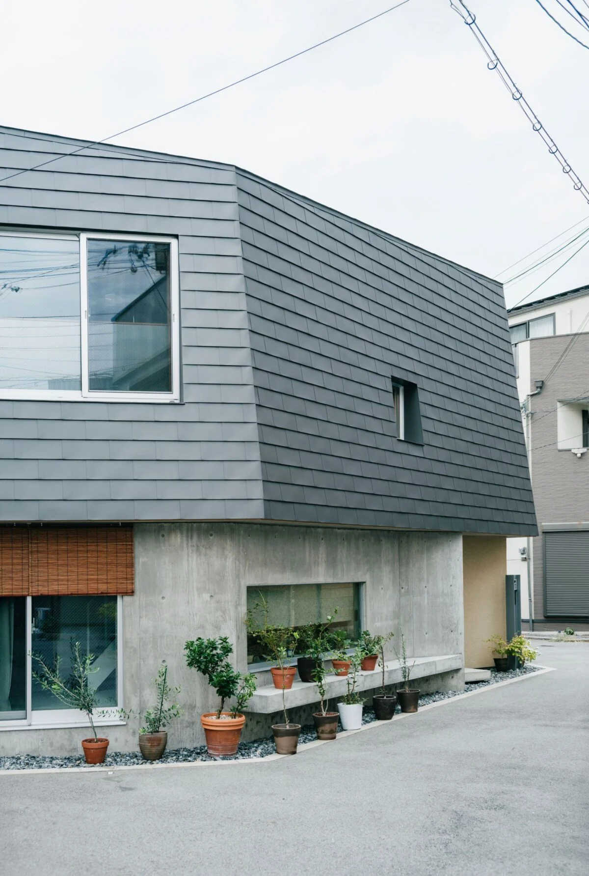 道路の幅に対して面が広いと「壁」の印象が強まってなじみにくくなるため、屋根や壁を多面的に分割。軒先に設けたベンチでは、ご近所のおばあちゃんが休憩する心温まる光景も
