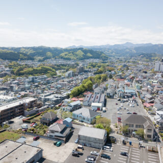 青梅の街並み。写真中央のパステルブルーの建物が、都立繊維試験場だったシネマネコ。敷地周囲には、倉庫をリノベーションしたダイニング＆ギャラリー、旧織物加工工場のさくらファクトリー工房、100名収容可能なホールを持つ協同組合本館があり、４棟が国登録有形文化財に指定されている。