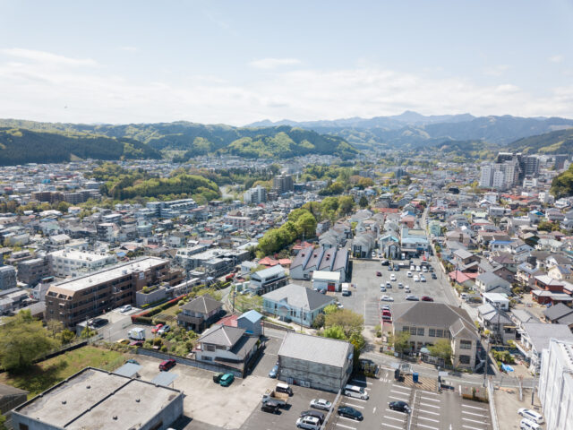 青梅の街並み。写真中央のパステルブルーの建物が、都立繊維試験場だったシネマネコ。敷地周囲には、倉庫をリノベーションしたダイニング＆ギャラリー、旧織物加工工場のさくらファクトリー工房、100名収容可能なホールを持つ協同組合本館があり、４棟が国登録有形文化財に指定されている。