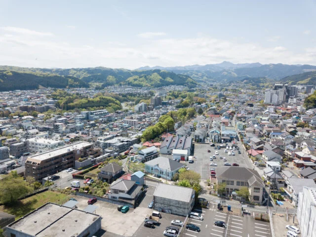 青梅の街並み。写真中央のパステルブルーの建物が、都立繊維試験場だったシネマネコ。敷地周囲には、倉庫をリノベーションしたダイニング＆ギャラリー、旧織物加工工場のさくらファクトリー工房、100名収容可能なホールを持つ協同組合本館があり、４棟が国登録有形文化財に指定されている。