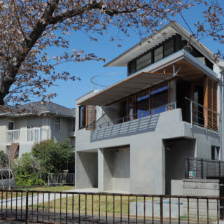 道路側から見た南西外観。この区画だけ長らく農地だった為、家が建つことで生まれる圧迫感を最小限に抑えるよう周囲の隣家との距離や対峙する壁面の大きさを調整した。正面は鋭角にセットバックすることで両隣の家の植栽が自然に連続している
画像：木島千嘉建築設計事務所　提供