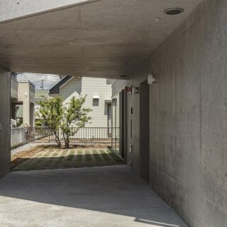 道路側からポーチ越しにカーポートを見る。右壁面、中央の切れ目を入ると玄関。正面は元々敷地に生えていたミカンの木