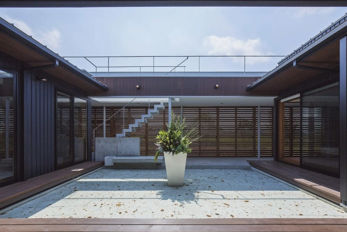 ピロティの建具を閉めた中庭をLDKから見る。南の庭との間に設けられたピロティは、オリジナルの建具付き。木製の水平スリットの間には網が仕込まれていて、中庭を含む住空間のプライバシーを守ると共に、周囲の田畑のカエルや虫が入りにくいようにする役割も兼ねている