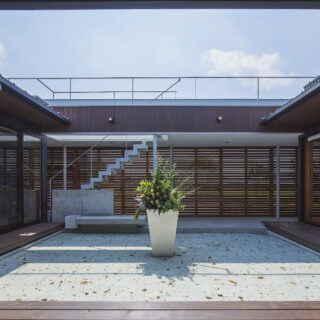 ピロティの建具を閉めた中庭をLDKから見る。南の庭との間に設けられたピロティは、オリジナルの建具付き。木製の水平スリットの間には網が仕込まれていて、中庭を含む住空間のプライバシーを守ると共に、周囲の田畑のカエルや虫が入りにくいようにする役割も兼ねている