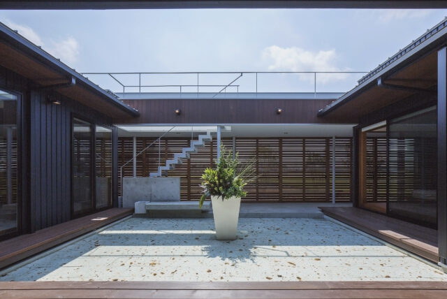 ピロティの建具を閉めた中庭をLDKから見る。南の庭との間に設けられたピロティは、オリジナルの建具付き。木製の水平スリットの間には網が仕込まれていて、中庭を含む住空間のプライバシーを守ると共に、周囲の田畑のカエルや虫が入りにくいようにする役割も兼ねている