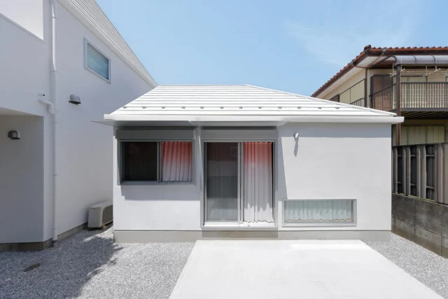 「Slur House」はコンパクトな平屋の離れ。母屋（写真左）の方に寄り添うような佇まいが微笑ましい。写真は南の庭から見た外観。庭は母屋と共用でき、バーベキューなども気軽に楽しめるように土間コンクリートで仕上げた。将来はウッドデッキを張ることも想定している