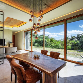 「RETREAT HOME」ダイニング（手前）リビング（奥）。最奥の通路を入ると主寝室。画像左、テレビがある壁面の裏にはウォークスルークローゼットがある。床は、庭から砂や土が入り込んでも掃除がしやすい、石目調のタイルを採用した