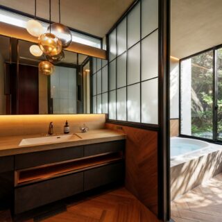 「RETREAT HOME」洗面（左）浴室（右）。洗面の鏡には主寝室の様子が映っている。浴室の窓の外は「陰」エリア。窓を開ければ緑と水の香りだけでなく、そばを流れる川の水音も聞こえる