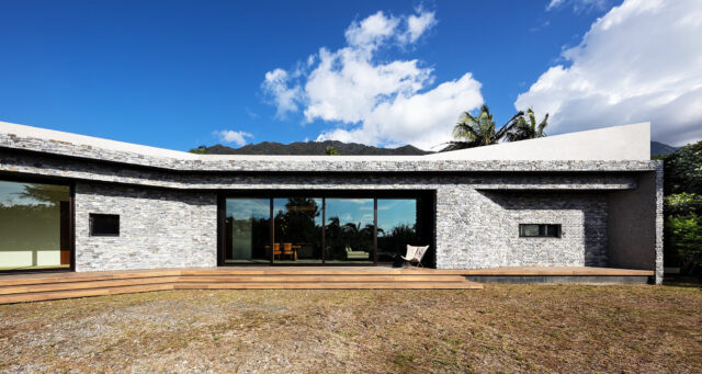 庭側から見た「RETREAT HOME」外観。建物はRC造。この地域では湿気で苔むしてしまうなど、外壁を美しく保つのが難しいという。そこで経年による変化が趣になる石壁を採用。あえて石をランダムに積んで自然な表情に。さらに大判タイルと組み合わせモダンな印象を演出した