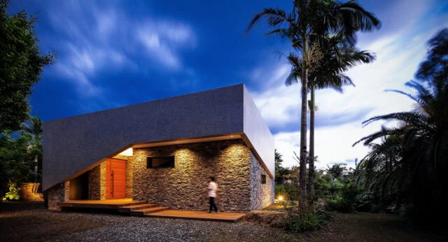 駐車場側から見た「RETREAT HOME」。赤い木製ドアが玄関。一直線に建物を計画すると斜めになってしまうところを、折り曲げたことで出迎えにふさわしい顔を持ったエントランスにすることができた