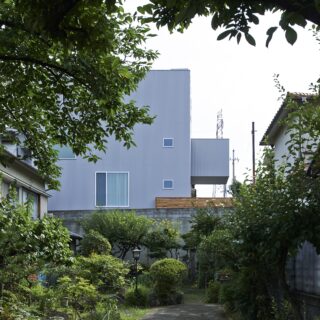 四方を隣家に囲まれたロケーションに建つ家。建築時は写真の通り、南西方向が抜けていたが、数年後に4棟の分譲住宅が建ち、現在では1階リビングの窓近くまで屋根が迫っている。
