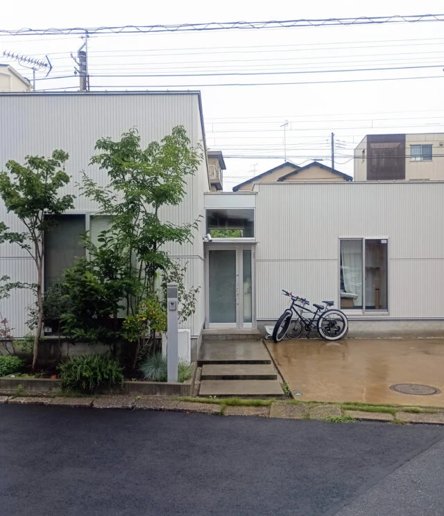 通り土間を中心に、寝室・水廻り棟とリビング棟を東西に配置したシンメトリーな構成。通り土間は外と内を緩やかにつなぐバッファとなり、東西棟を分ける“あいまいな空間”にもなっている
