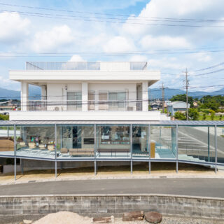 増築部側の外観。側面は全面ガラスで、内側に既存建築のビシャン仕上げの外壁が見える。40年前に建てられた既存建築の歴史を感じつつ、スロープ・キッズエリア・余裕のある待合室など最新の快適な空間も得ることができた。増築という選択肢の価値がよくわかる