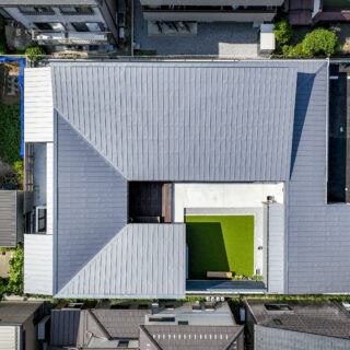 真上から見ると、建物が蛇行しながら中庭を囲んでいるのが分かる。四方を塞がず一箇所を開けることで、風の通り道と外部との接点を残した。屋根は中庭に向かって低くなる片流れに。　