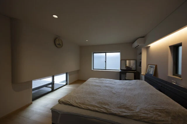 中庭側の屋根が低いぶん、隣家からの視線が届く。そのため寝室には地窓を採用した。上部の壁を少し出してカーテンボックスを隠し、埃が目立たないよう配慮している。