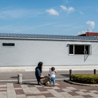 公園側から見た外観。周囲となじむように配慮されている。屋根の高さはできるだけ抑え、圧迫感を感じないように。外壁はガルバリウム。波トタンを横に貼り、高さを感じさせない。シルバー色は天候や周囲の緑を反射し、なじむものとなっている