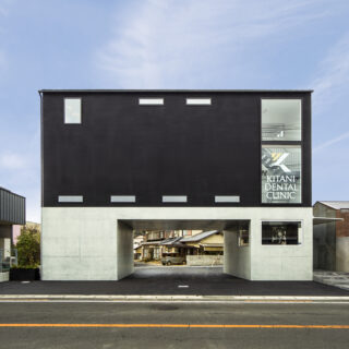 外観。周辺の建物よりも背が高いため、前面道路から距離を取り圧迫感をなくした。裏の道路まで通り抜けられることで、駐車時・退出時の混雑を軽減。また、1階の壁面をL字に開口し、道路までの見通しをよくした。本館利用者は、開口部や建物右のアプローチから行き来できる