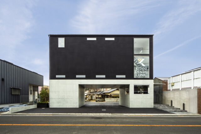 外観。周辺の建物よりも背が高いため、前面道路から距離を取り圧迫感をなくした。裏の道路まで通り抜けられることで、駐車時・退出時の混雑を軽減。また、1階の壁面をL字に開口し、道路までの見通しをよくした。本館利用者は、開口部や建物右のアプローチから行き来できる