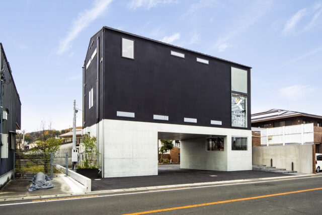 外観。建物の長辺に対しては表裏に道路が走っており、また隣家との距離もあることからすべての面の外壁が見える。そこで、右隣に本館があることから左側の外壁を建物の裏と設定し、配管などを集めた。美しく整えられた管のラインがスタイリッシュかつワイルドな印象
