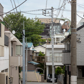 写真中央上に見える、黒と大窓の外観が特徴的な建物がF邸。大田区馬込の住宅密集地の崖地に立地