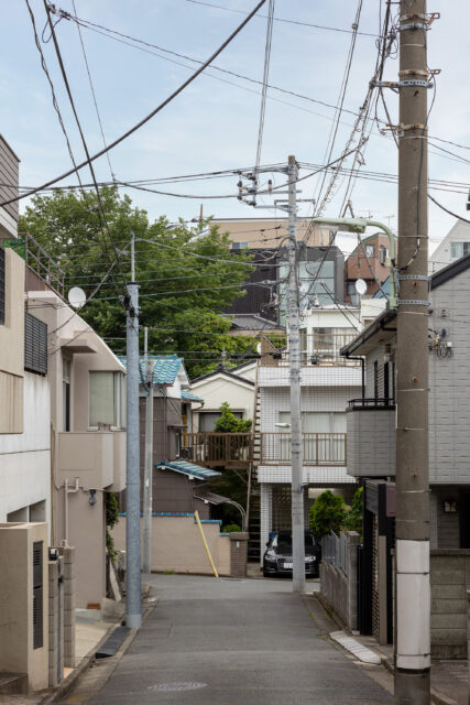 写真中央上に見える、黒と大窓の外観が特徴的な建物がF邸。大田区馬込の住宅密集地の崖地に立地