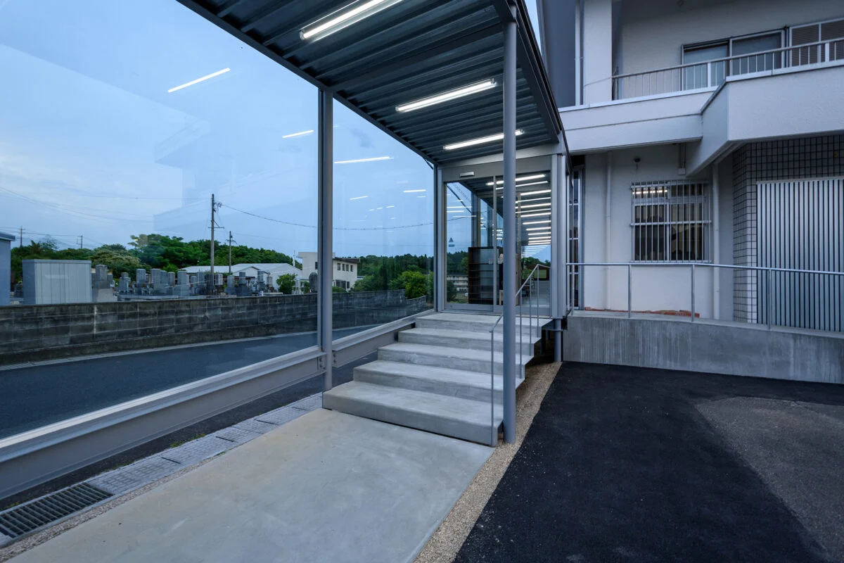 緩やかなスロープや増築部の緩やかな段差とあわせ、入り口の階段部もかなり緩やかなものとした。外と中の連続性を持たせた意匠だ。歩行する際の安定性や安心感、緩やかな表情を入り口に持たせる意図もある
