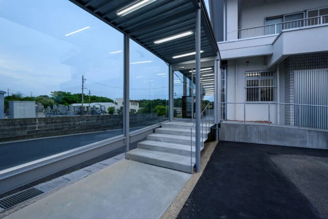 緩やかなスロープや増築部の緩やかな段差とあわせ、入り口の階段部もかなり緩やかなものとした。外と中の連続性を持たせた意匠だ。歩行する際の安定性や安心感、緩やかな表情を入り口に持たせる意図もある