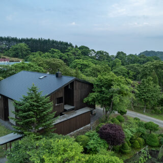 カラマツを木酢液に漬け込み、対候性と風合いを出した「木の箱」と、グレーの「左官の箱」、2種類の素材の箱をバラバラに配置。それらを大きな屋根が統合している。お施主さまの要望で雪が落ちるよう屋根には傾斜をつけた