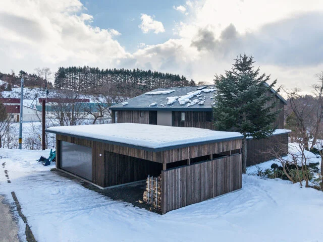 車庫側から見た外観。隣接する屋根付きの建物から母屋の室内にアプローチできる 