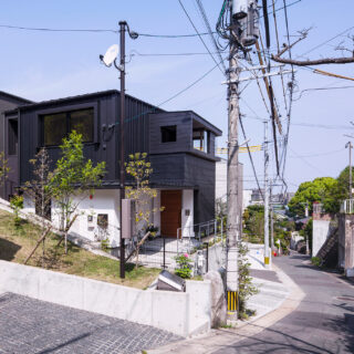 敷地全体を住まいと考え、擁壁や駐車場を含む外構や植栽までトータルに提案。街並みに調和しつつも存在感を発揮する「ここにあるべき一邸」をデザインした。