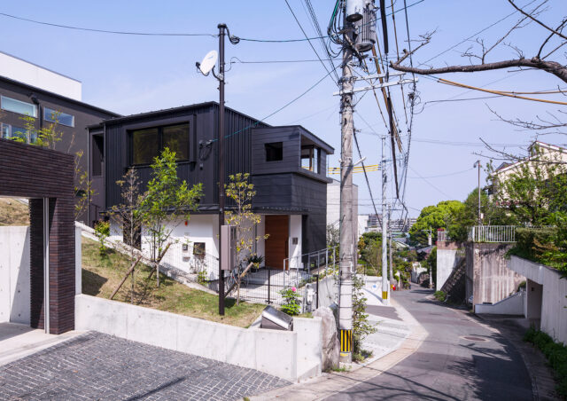 敷地全体を住まいと考え、擁壁や駐車場を含む外構や植栽までトータルに提案。街並みに調和しつつも存在感を発揮する「ここにあるべき一邸」をデザインした。