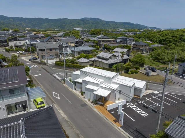周辺の住宅地を望む。右手の木々に覆われた小高い森も、古墳だという。昔ながらの瓦屋根の家と新しい家が混ざり合う中に、ボリュームを小分けにした白いクリニックがなじむ。