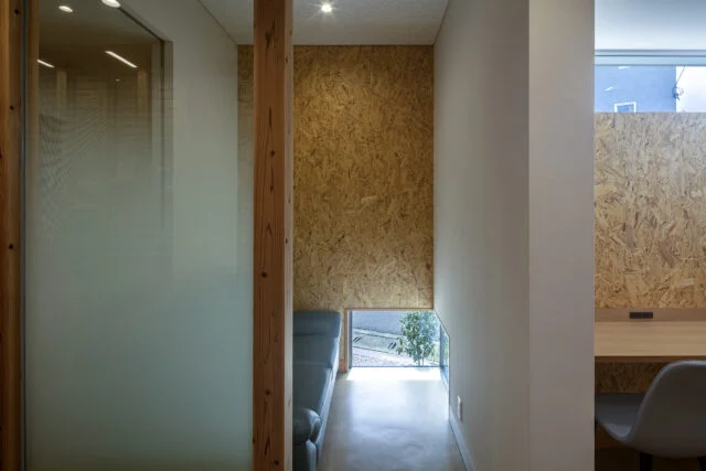 個室待合の内部。付き添いの人と二人で待てる部屋で、足元の地窓から植栽の緑がのぞく。右手はプライベート待合のカウンター席。