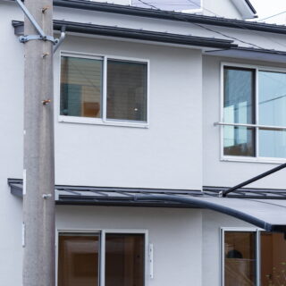 薄いグレーの左官仕上げの外壁に、ガルバリウム鋼板の屋根。屋根に載る塔屋は、2階に陽が入らないという問題を解くために生まれた。平面から45度振った高窓が南の光を取り込み、開け放てば重力換気で熱が抜けていく