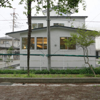 東側の校庭から見たN邸。手前に立つのが、借景として取り込んだ桜の木。1階の窓が高い位置にあることも見て取れる