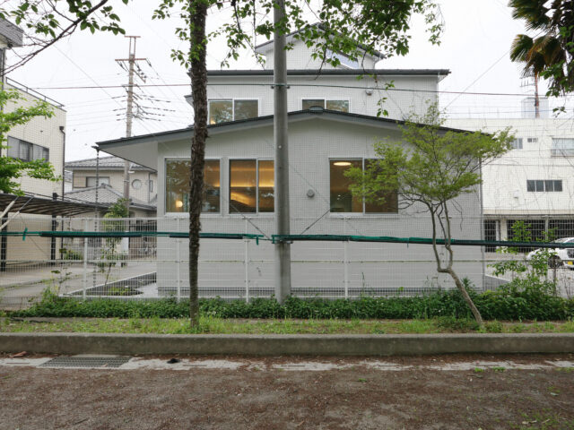 東側の校庭から見たN邸。手前に立つのが、借景として取り込んだ桜の木。1階の窓が高い位置にあることも見て取れる
