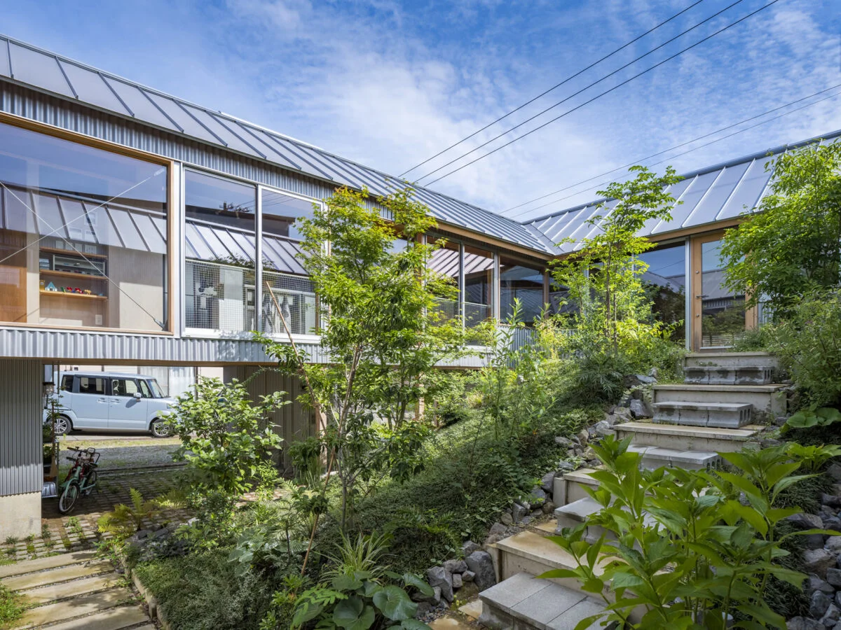 中庭を散策する気分で丘状のアプローチを登り住居の玄関へ。現在は写真の3倍ほどのボリュームで木々や植物が茂り、収穫したベリーでジャムを作ったり、山菜を調理して食べたりと、庭のある暮らしを楽しんでいる